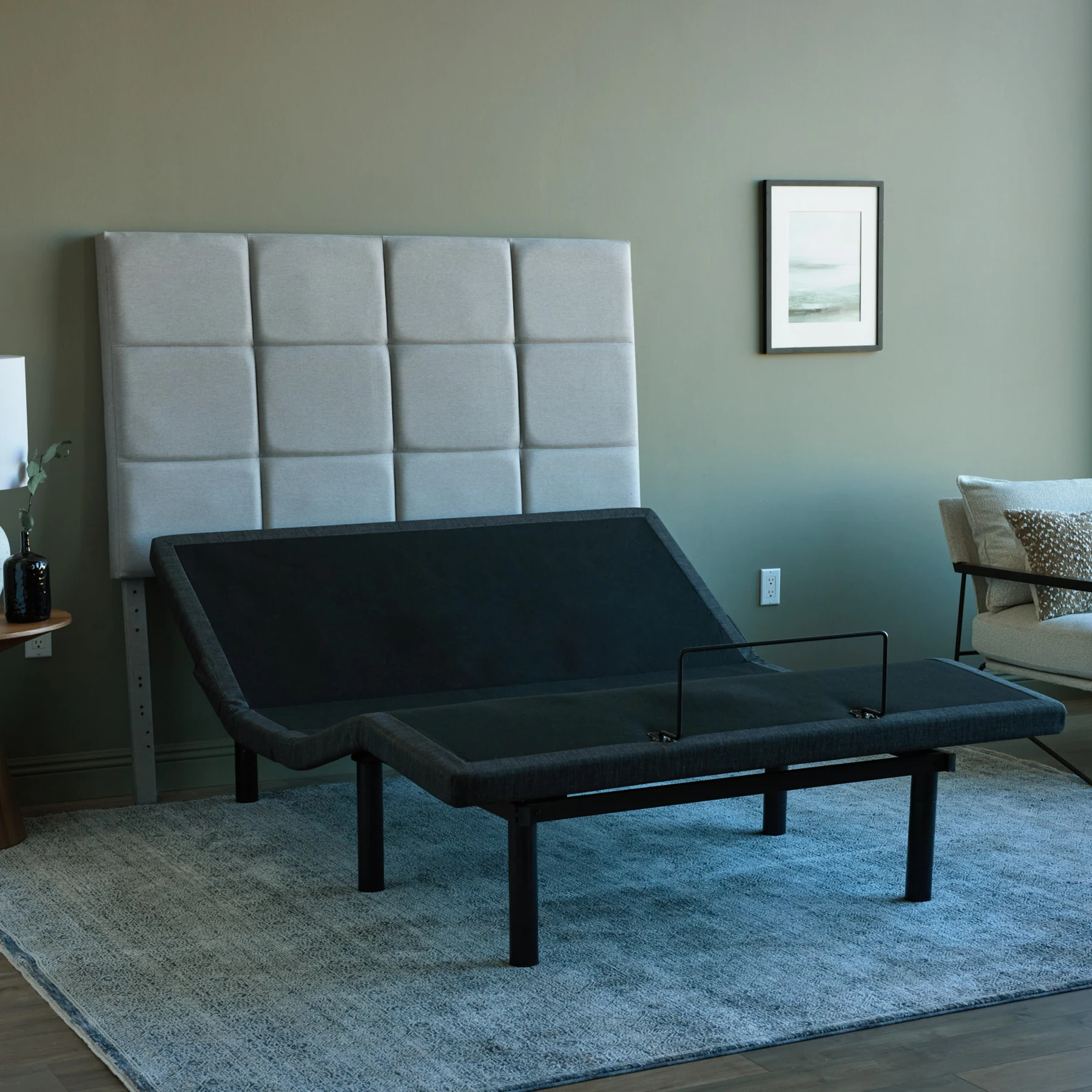 Malouf M555 adjustable bed base raised in a bedroom with an upholstered headboard