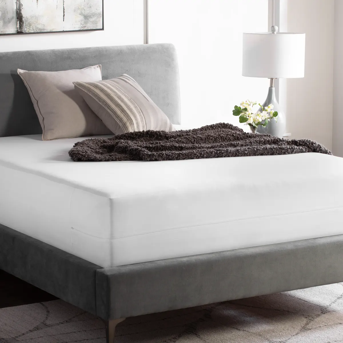 White zippered mattress encasement on a bed with a gray upholstered frame