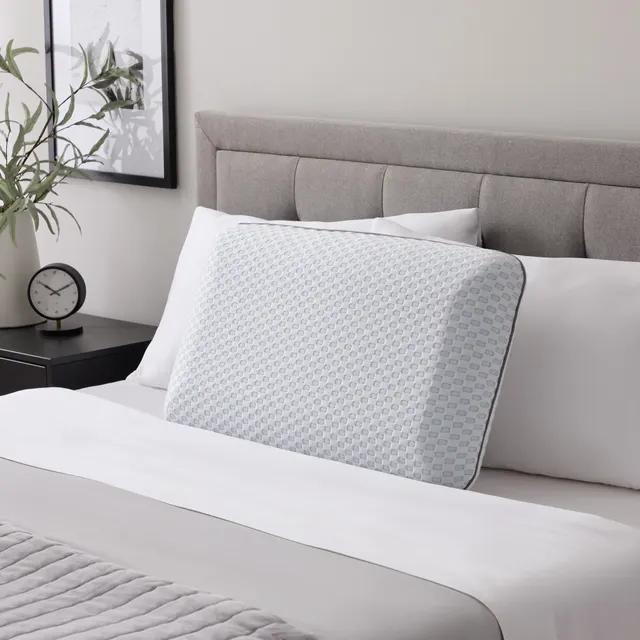 Memory foam pillow with a patterned cover on a made bed