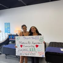 Two customers holding a handwritten thank-you sign in the showroom