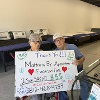 Two customers holding a handwritten thank-you sign in the showroom