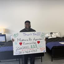 Customer in a black cap holding a handwritten thank-you sign in the showroom