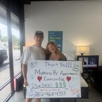 Two customers holding a handwritten thank-you sign in the showroom