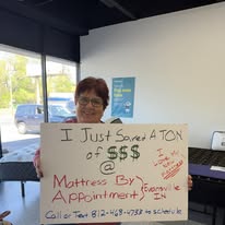 Customer holding a handwritten sign about saving on a mattress