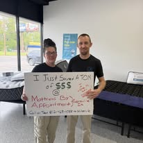 Two customers holding a handwritten thank-you sign in the showroom